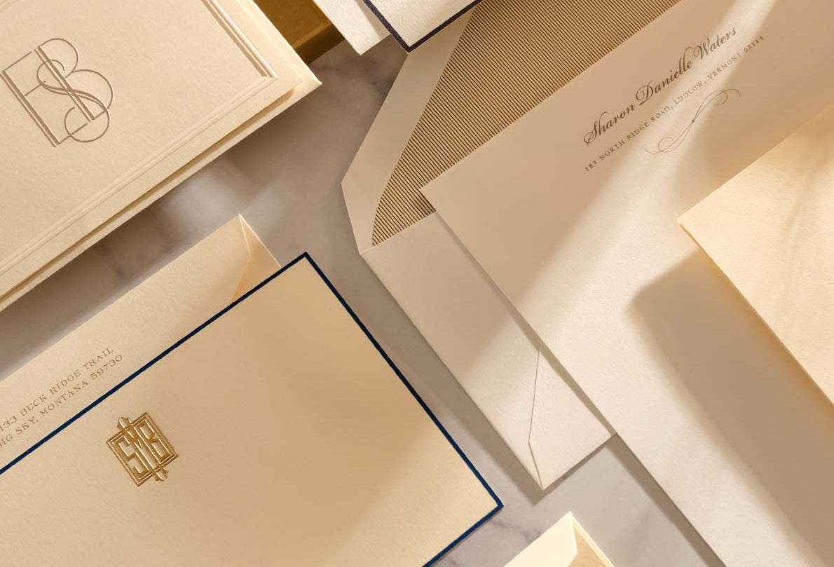 Collection of elegant envelopes and letterheads with gold and beige tones.